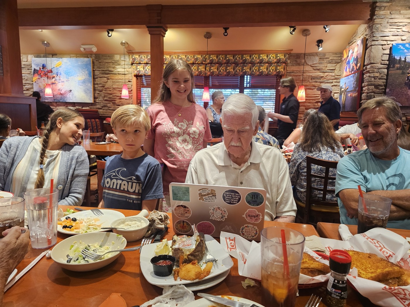 Family gathered around a laptop at a restaurant table