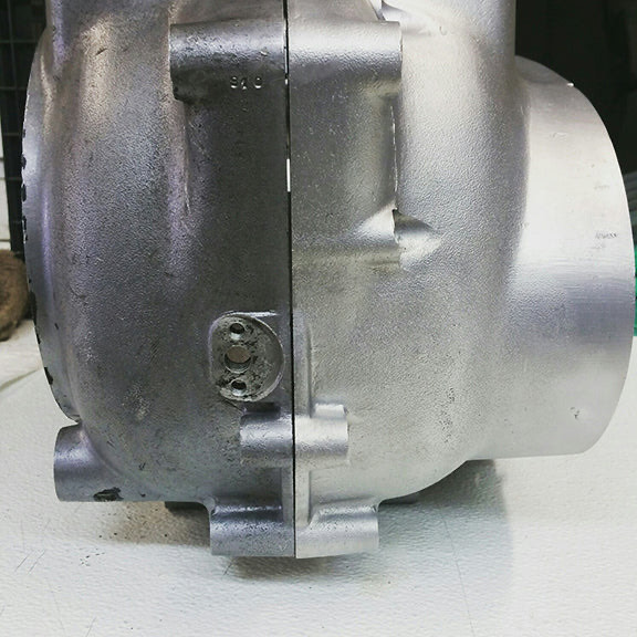 A single engine housing photographed mid job, the left half still dark with grime and the right half cleaned to bright aluminum